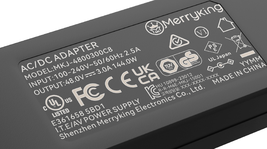 Close-up of a laptop charger specifications label detailing dual voltage input 100 to 240 volts